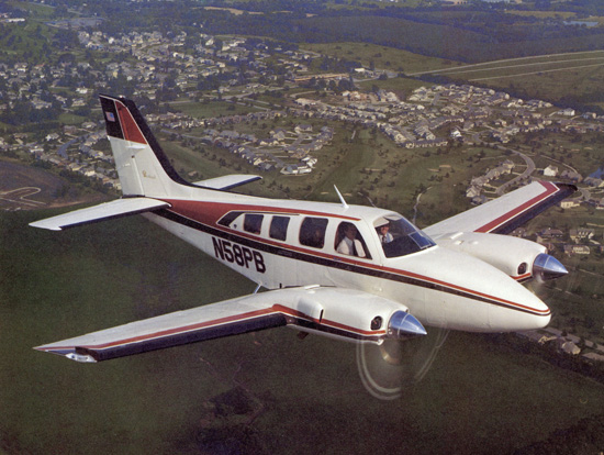 Beechcraft Baron 58 in flight over a town